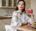Beautiful serious woman drinking juice while having breakfast in cozy kitchen